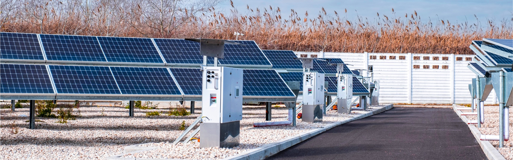 Photovoltaic plant with solar panels installed on gravel ground, alongside electrical substations
