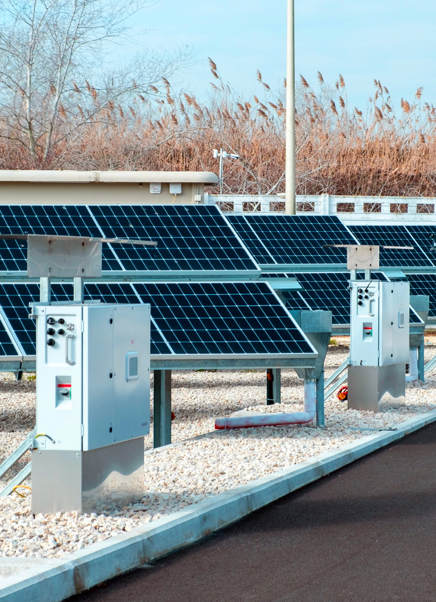 Photovoltaic plant with solar panels installed on gravel ground, alongside electrical substations