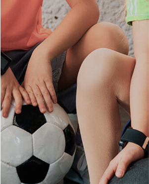 Detail of the hands of two children resting on two footballs