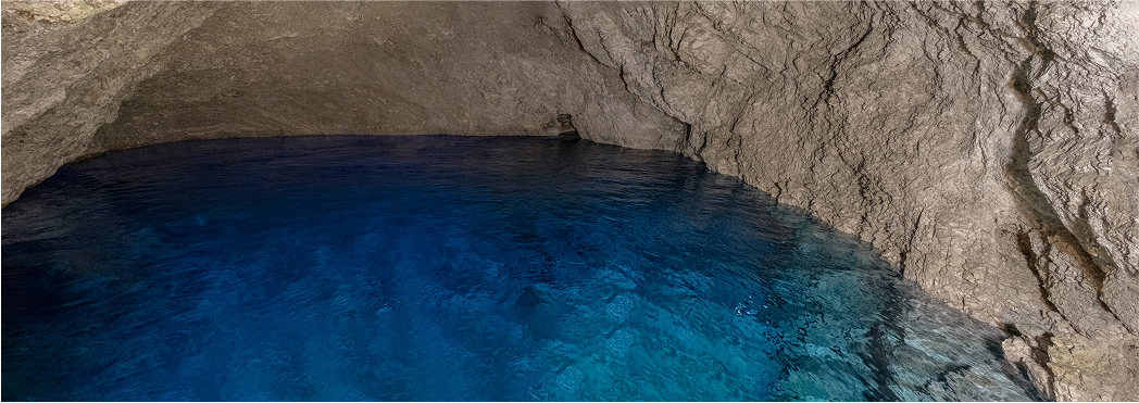 Cave with crystal clear blue water and rocky walls