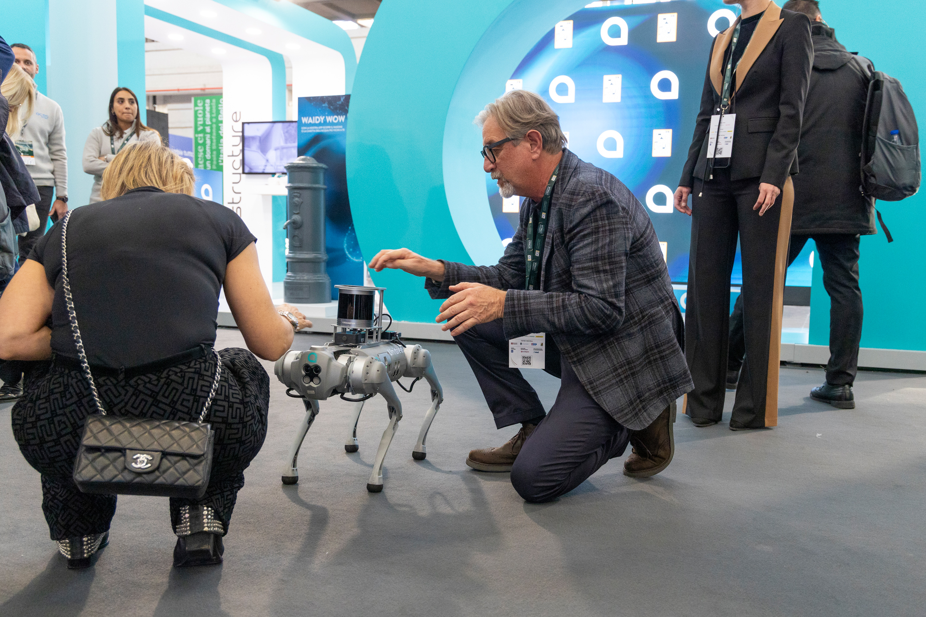 due persone inginocchiate che interagiscono con il robot acea a forma di cane