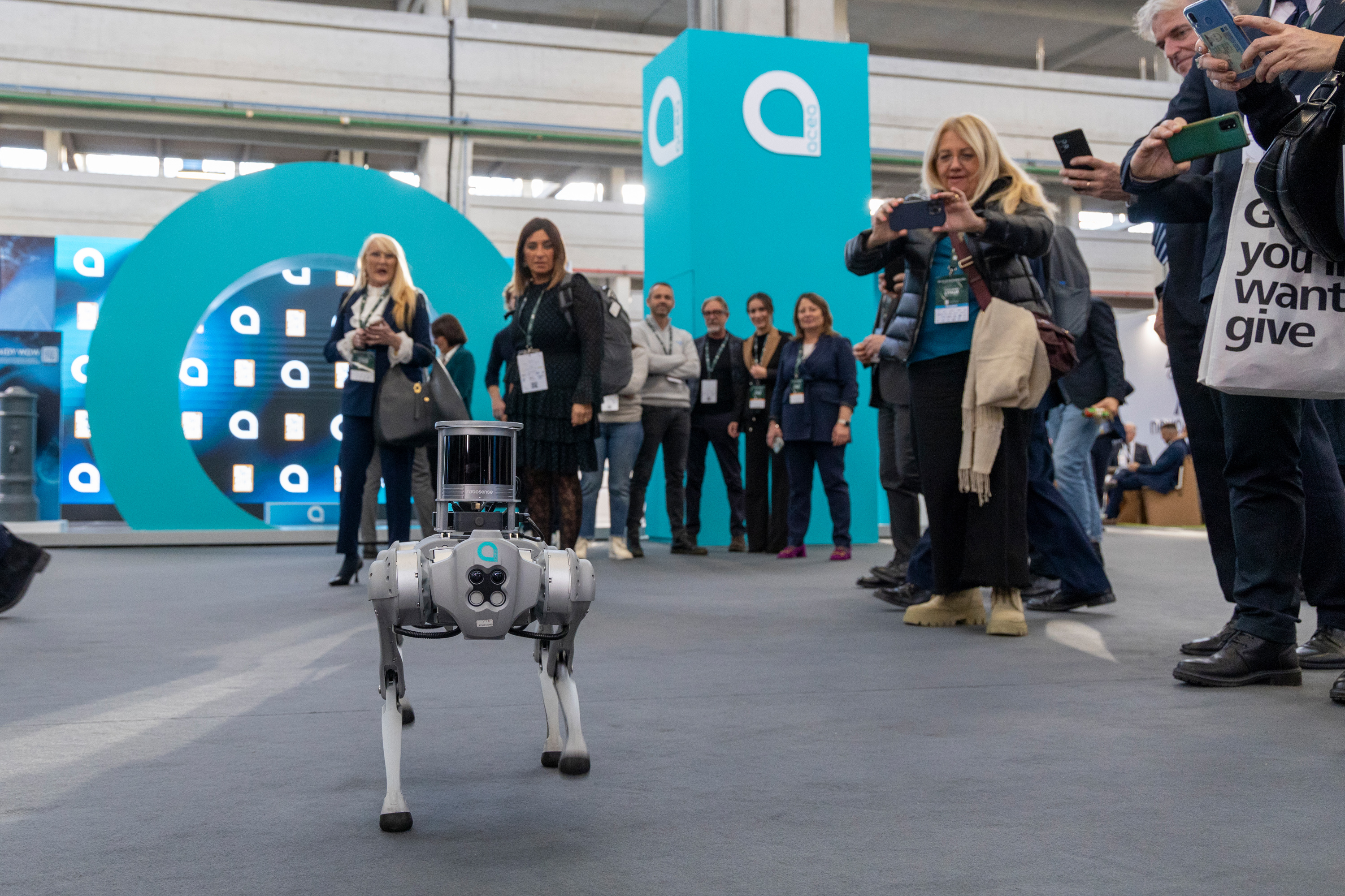Gruppo di partecipanti all'evento che guardano e fotografano il robot a forma di cane