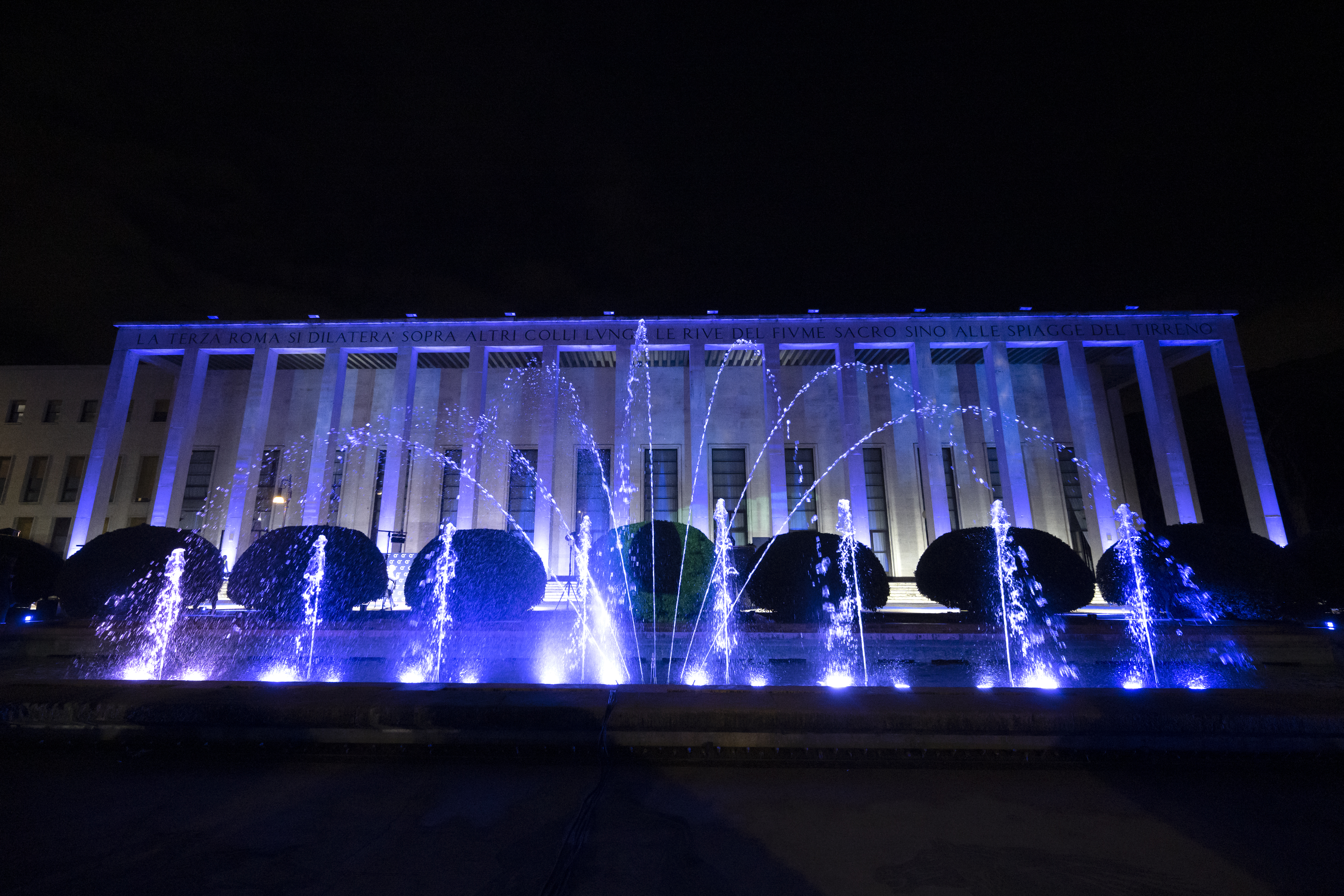 a blue-lit fountain behind a building