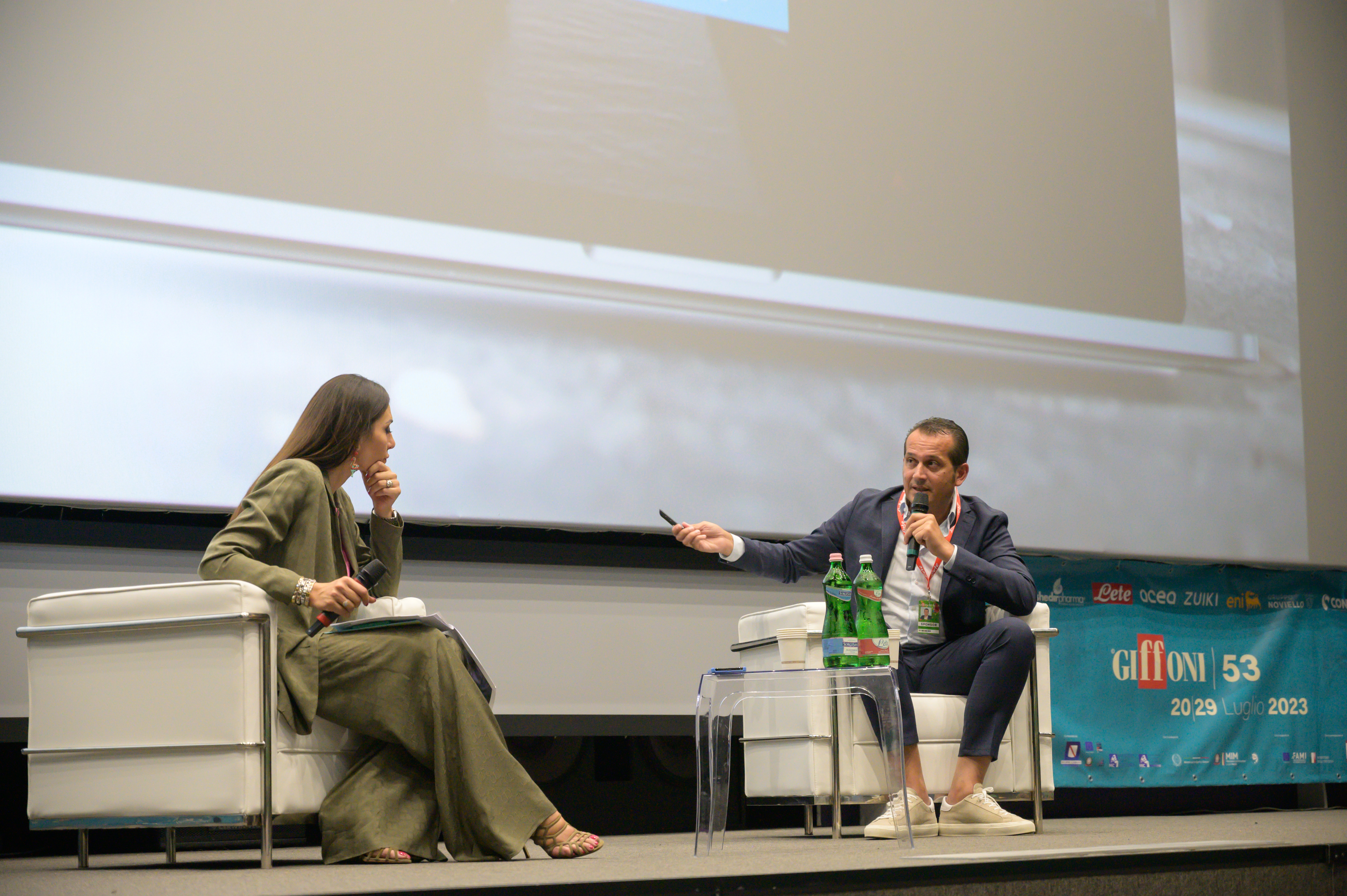 two people sitting on armchairs give a speech