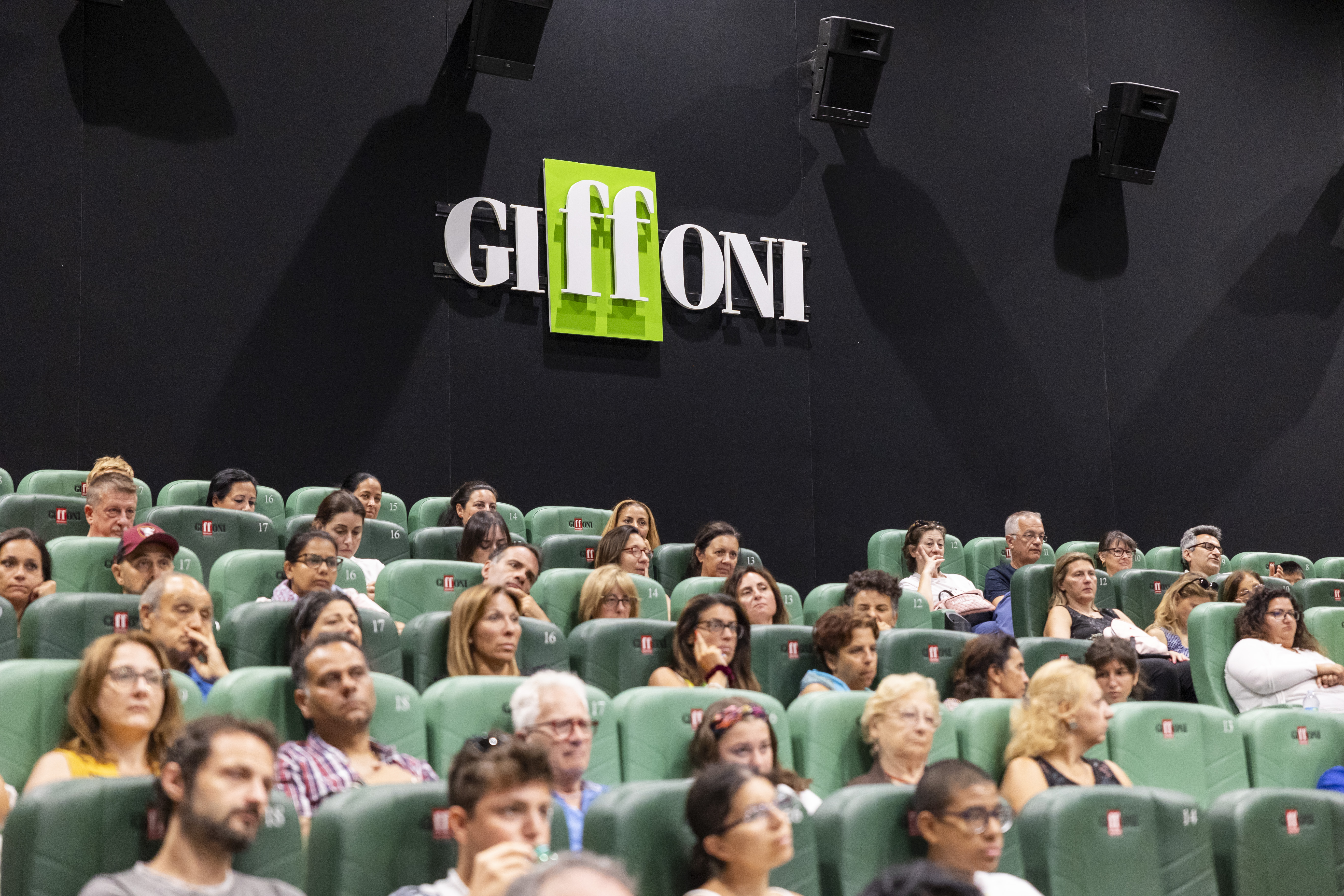 audience of people sitting on seats. Behind can be seen the Giffoni logo
