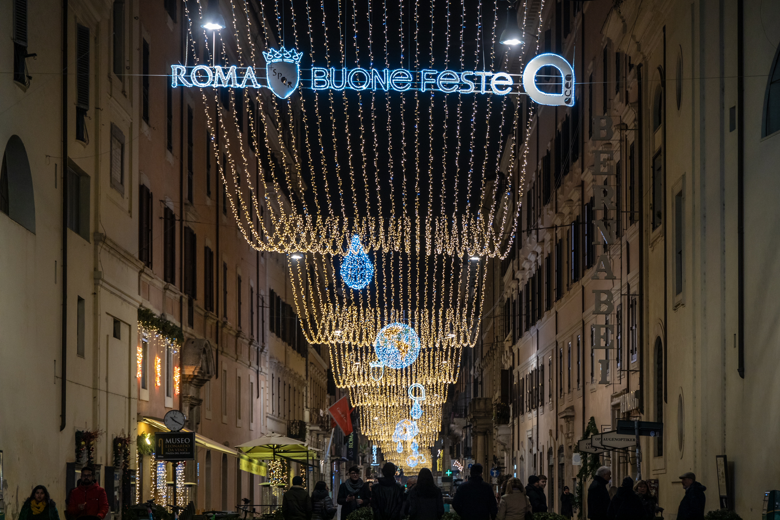 Primo piano delle luminarie accese con la scritta illuminata "roma buone feste" e il logo Acea