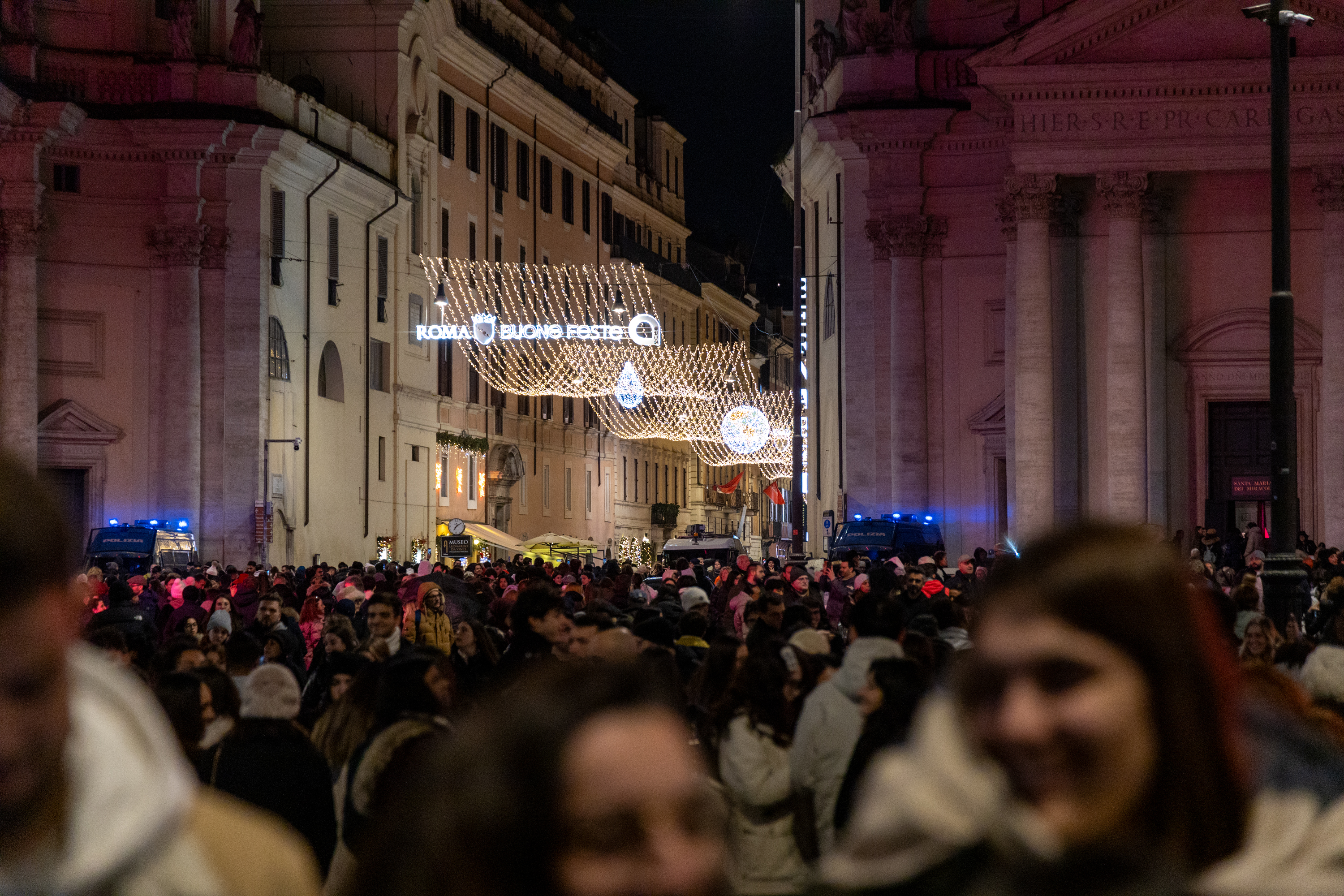 Folla di persone con l'entrata su via del corso e le luminarie sullo sfondo