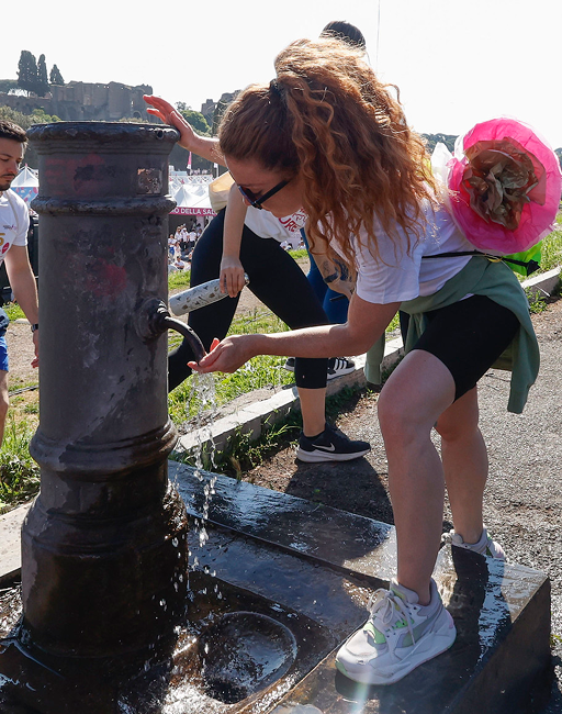 Donna si disseta da una fontanella pubblica durante l'evento Acea Run for the Cure