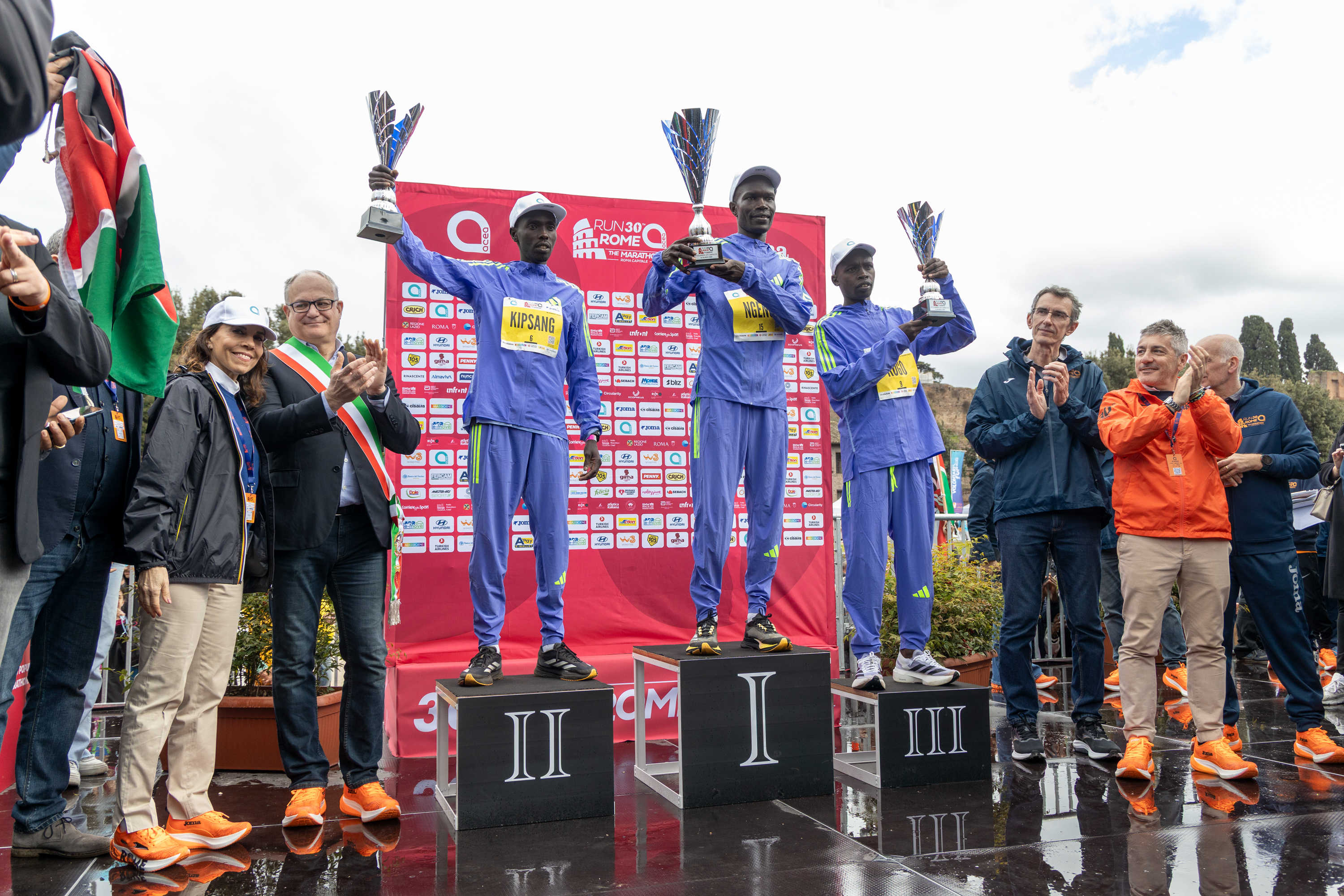 the three winners on the podium with their cups raised
