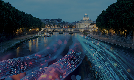 In the background is the Vatican and in front of it a bridge, both illuminated. Coloured electric cables run over the Tiber