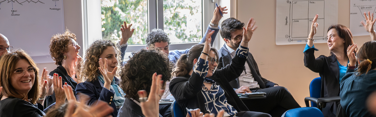 A diverse group of professionals actively participating in a collaborative session, raising their hands to engage. The bright environment and enthusiasm of the participants reflect the values of inclusion, diversity, and collaboration promoted by Acea.