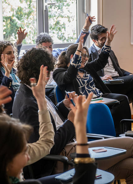 A diverse group of professionals actively participating in a collaborative session, raising their hands to engage. The bright environment and enthusiasm of the participants reflect the values of inclusion, diversity, and collaboration promoted by Acea.